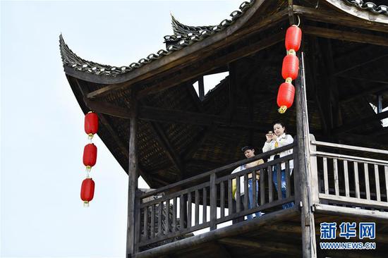  游客在重慶市武隆區(qū)黃鶯鄉(xiāng)復(fù)興村的觀景樓上欣賞田園景色（2019年3月28日攝）。 新華社記者 劉潺 攝
